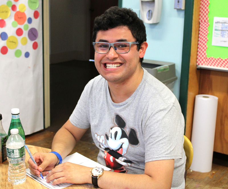 A smiling young adult seated at a table